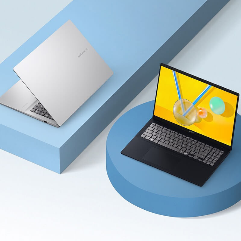 Zwei ASUS Vivobooks sind auf lila geometrischen Formen platziert. Das silberne Modell ist leicht geöffnet, während das schwarze Modell offen ist.